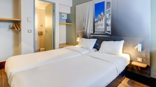 Habitación de hotel con una cama grande, baño con puerta de cristal y una obra de arte colgada en la pared.