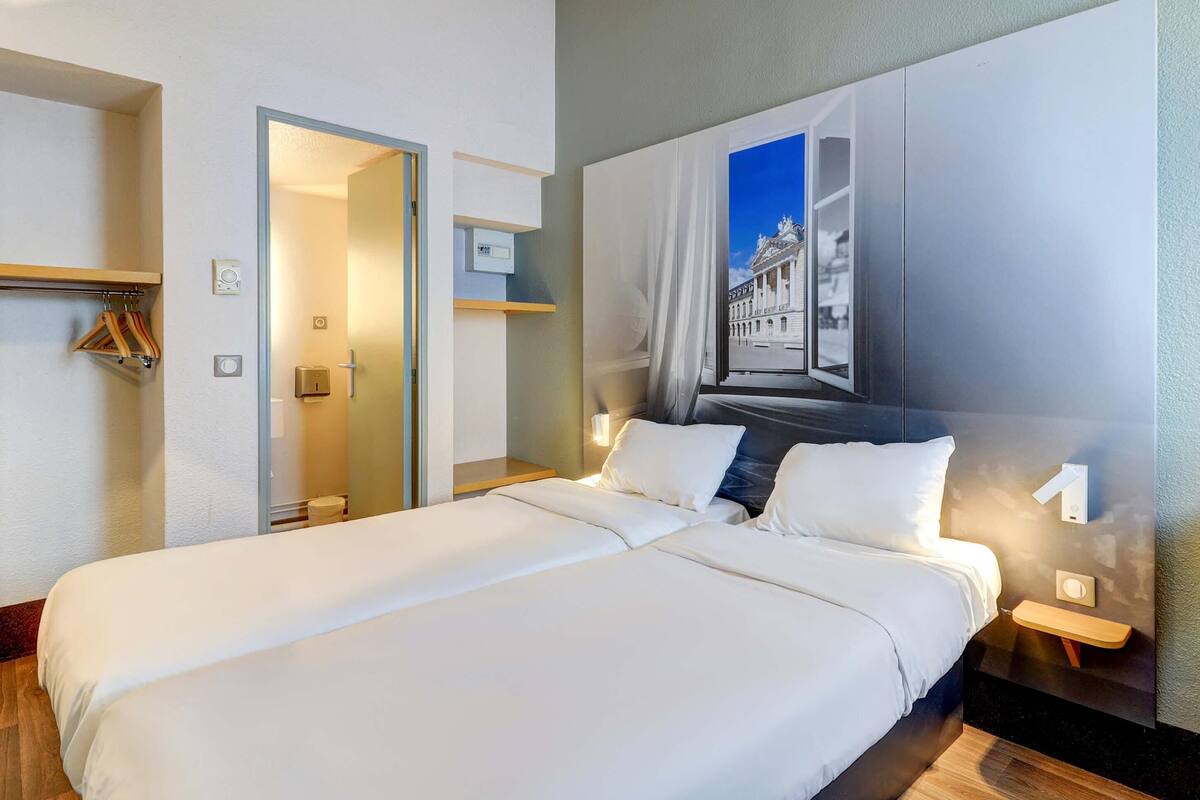 Habitación de hotel con una cama grande, baño con puerta de cristal y una obra de arte colgada en la pared.
