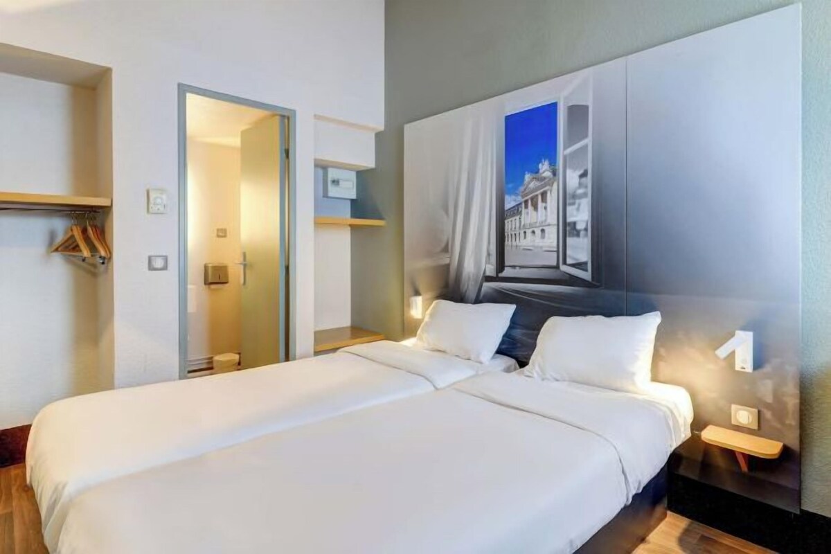 Habitación de hotel con una cama grande, un armario, un espejo y una obra de arte colgada en la pared.