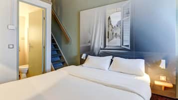Ein Hotelzimmer mit Bett, Badezimmer, Treppe und einem großen Fenster mit Blick auf eine Straße.