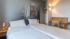 Una habitación de hotel con una cama, mesitas de noche, un escritorio y una silla.
