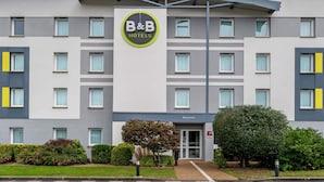 Un hotel tipo bed and breakfast con diseño moderno, que presenta una entrada central, varios ventanales y un jardín bien cuidado.