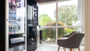 Máquina expendedora con un rótulo que dice 'PUSH', puerta de cristal y vista al exterior a través de un ventanal grande.