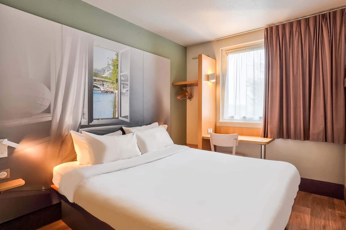 Habitación de hotel con una cama grande, un escritorio y vistas a una masa de agua.