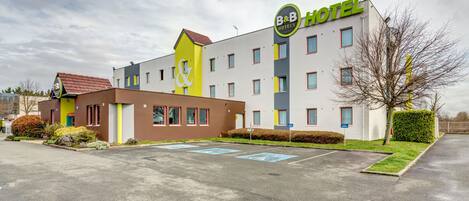 Un hôtel de type « bed and breakfast » au design moderne, avec un logo bien visible, de nombreuses fenêtres et un espace de stationnement.