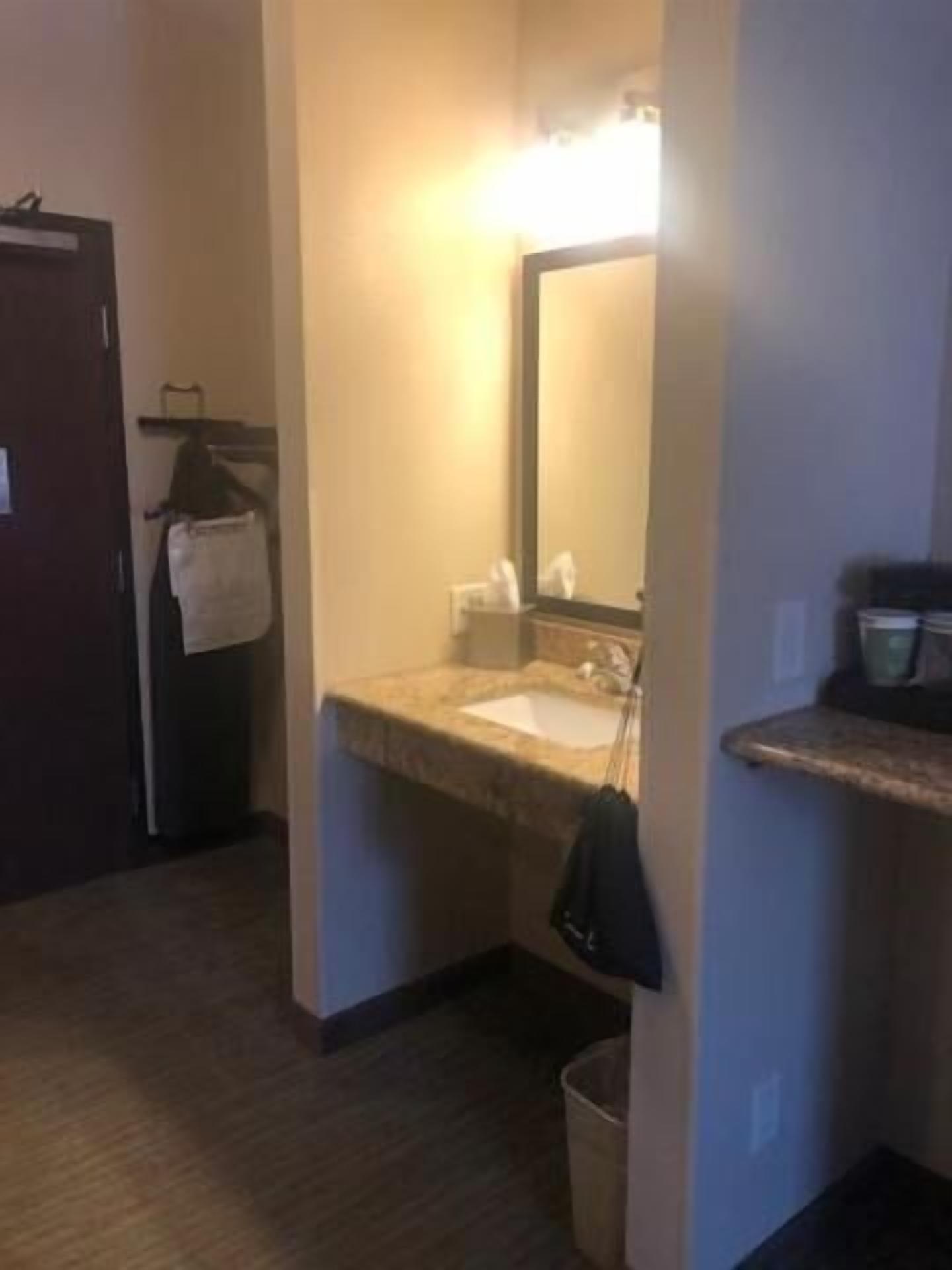 A small bathroom with a sink, mirror, towel rack, and a trash can.
