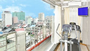 Un balcon avec un tapis de course et une vue sur la ville.