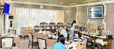 A dining area with multiple tables, chairs, and a buffet setup.