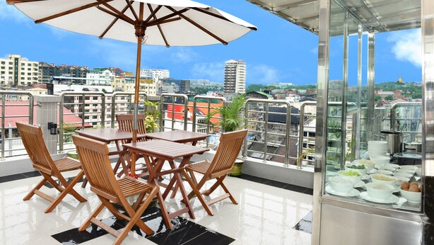 Une terrasse sur le toit, équipée d’une table à manger, de chaises et d’un grand parasol.
