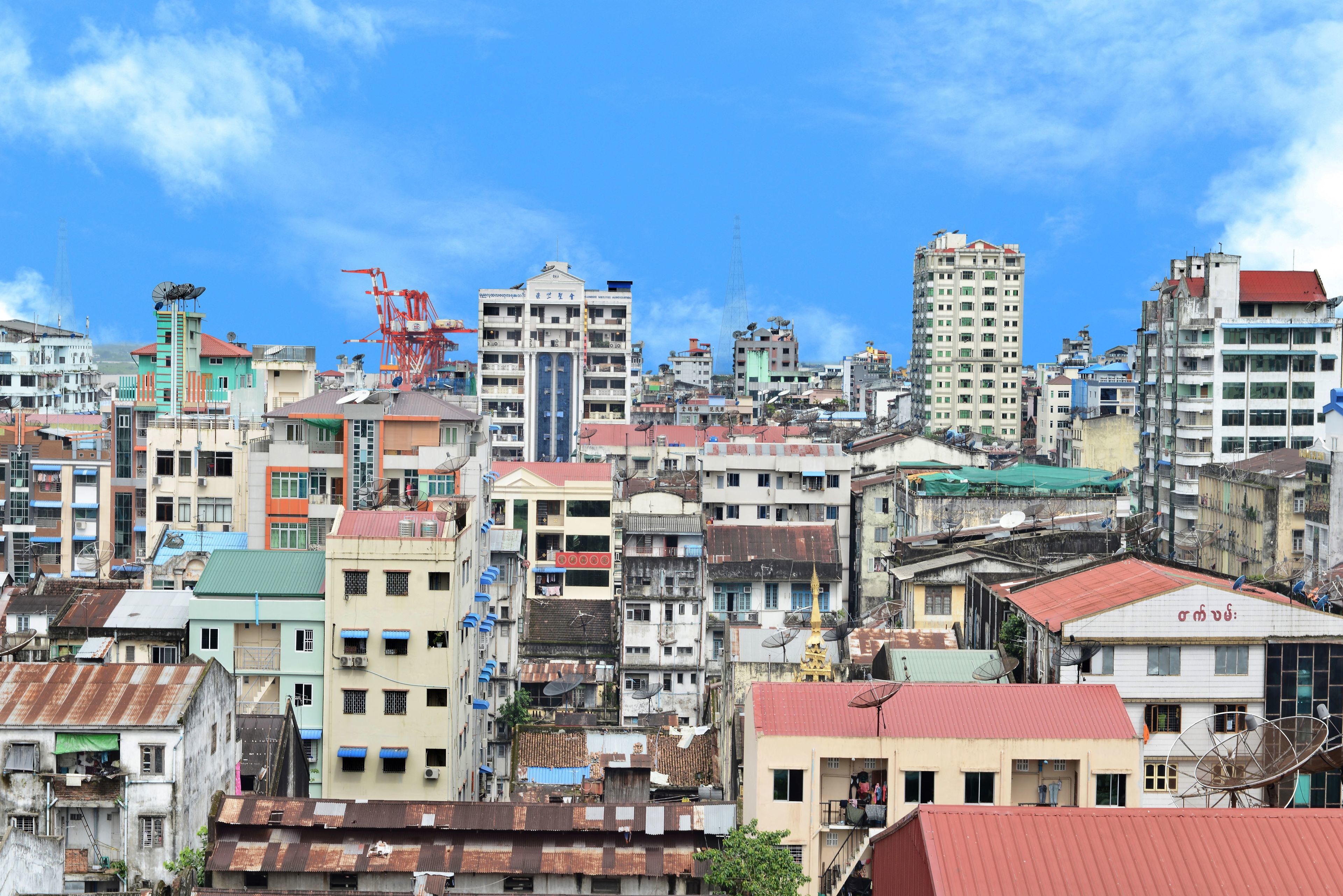 Una zona urbana densamente poblada con varios edificios de varios pisos, algunos con antenas parabólicas visibles, bajo un cielo azul despejado.