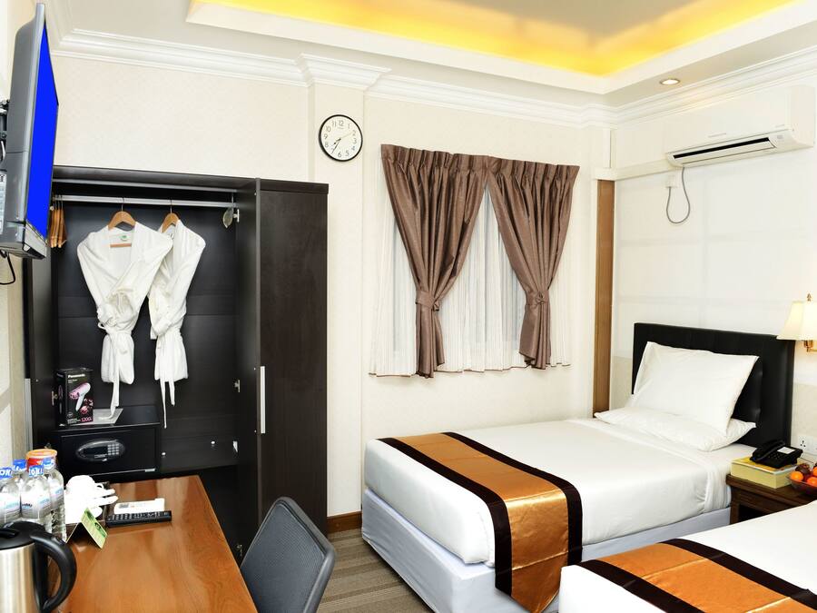 Una habitación de hotel con escritorio, dos camas, televisión, armario y reloj.