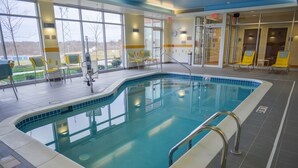An indoor swimming pool with clear glass walls, yellow chairs, and a tiled floor. - Fairfield Inn & Suites Canton South (Canton)