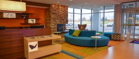 A reception area with a stone wall, a blue sofa with cushions, a small table, and a reception desk with a butterfly decoration.