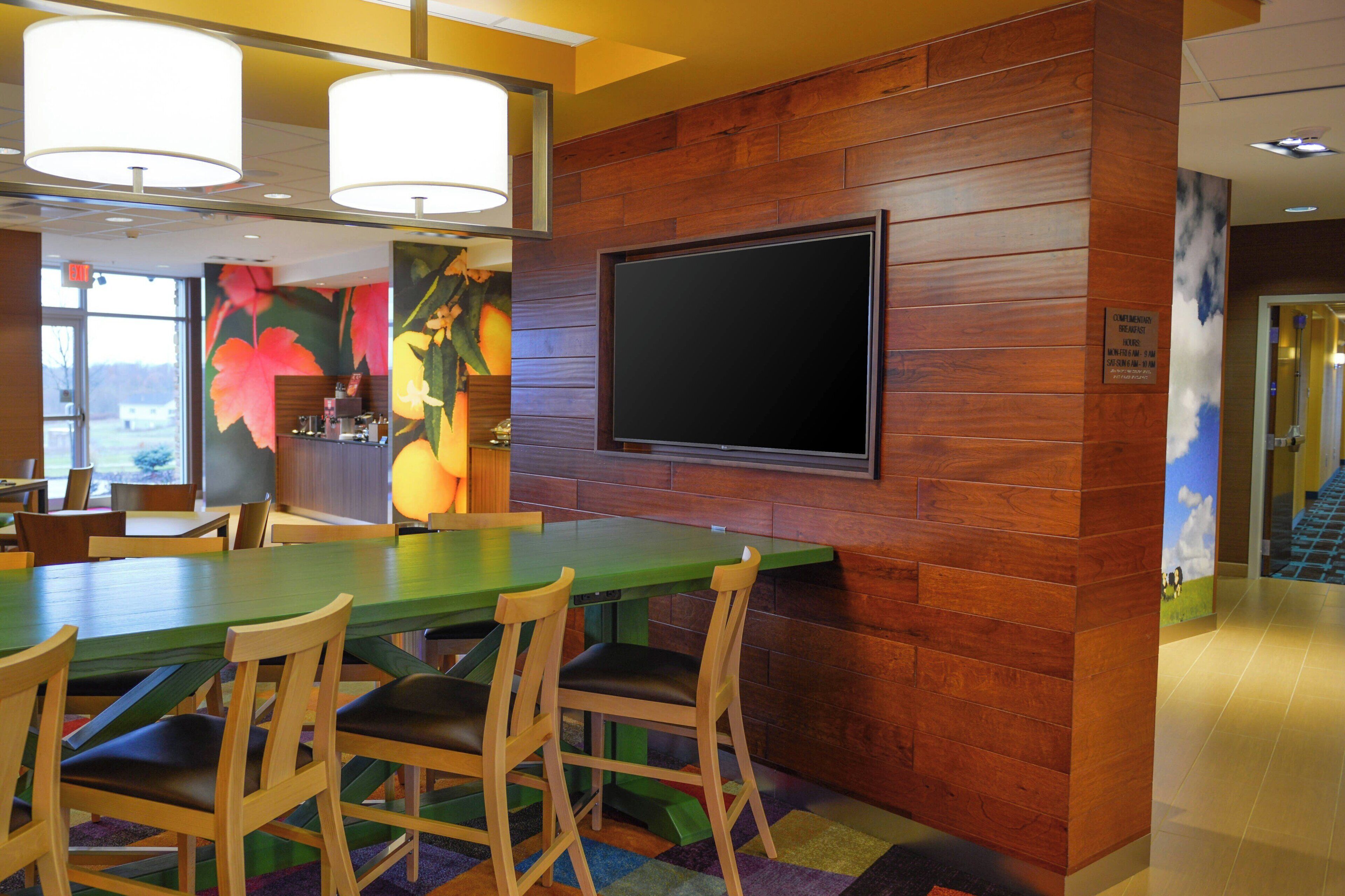 A conference room with a large table, chairs, a flat-screen TV, and a mural on the wall.