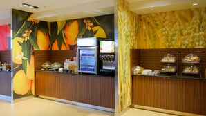 A breakfast bar with a refrigerator, coffee machine, and a display of pastries. - Fairfield Inn & Suites Canton South (Canton)
