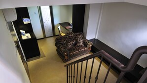Una escalera con barandal negro que conduce a una habitación con un sofá estampado y una mesita.