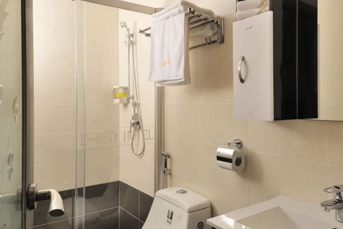 A modern bathroom with a glass shower enclosure, a toilet, a sink, and a towel rack.