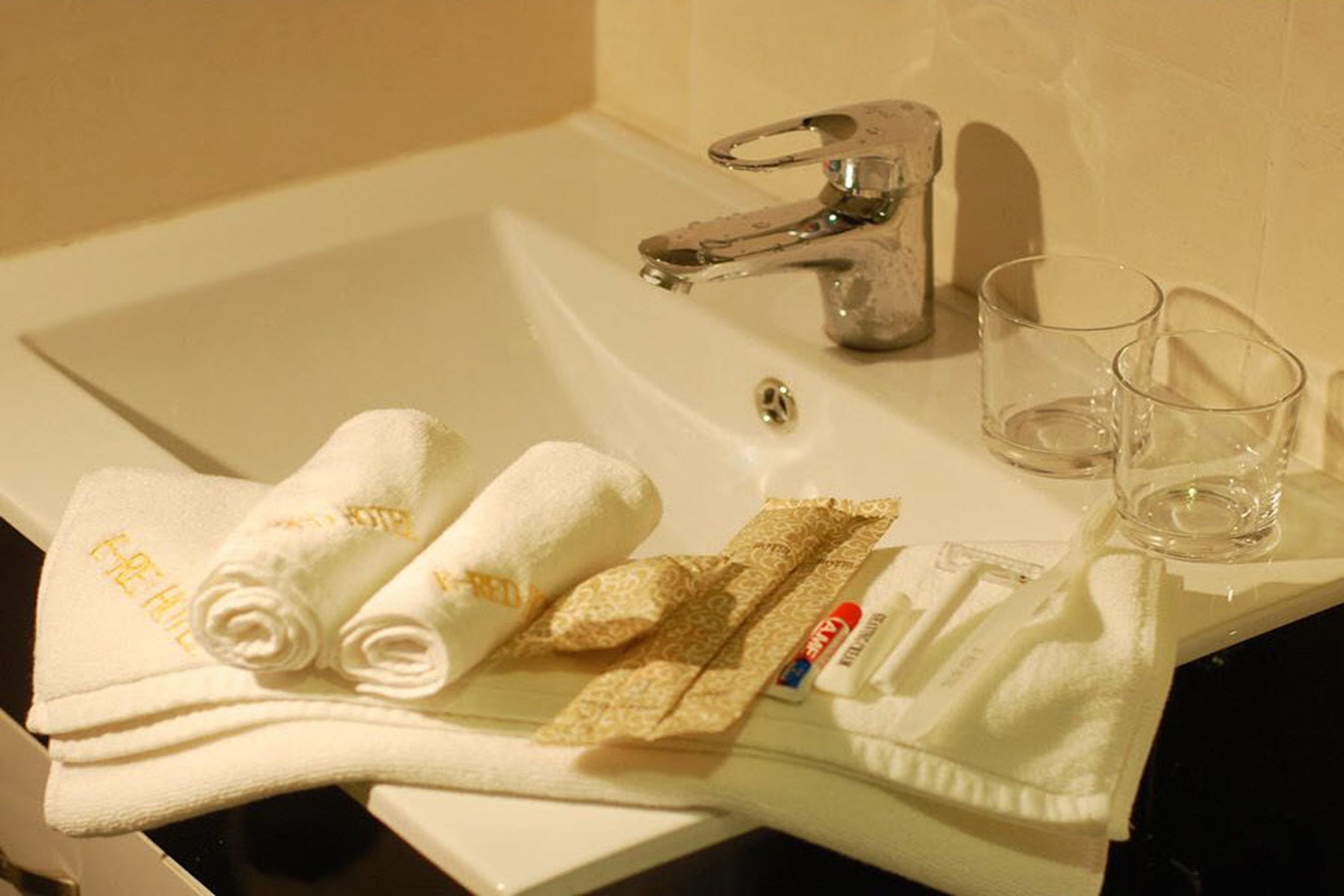 A hotel bathroom sink with two glasses, a towel, and a bar of soap.