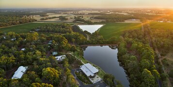 Vista aérea de una propiedad con un lago extenso, campos verdes y un puente que conecta diferentes zonas.