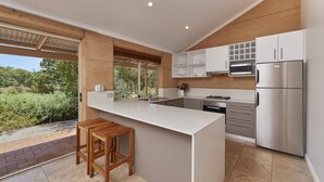 A modern kitchen with a large island, built-in appliances, and a view of greenery outside. - Eight Willows Retreat (Metricup)