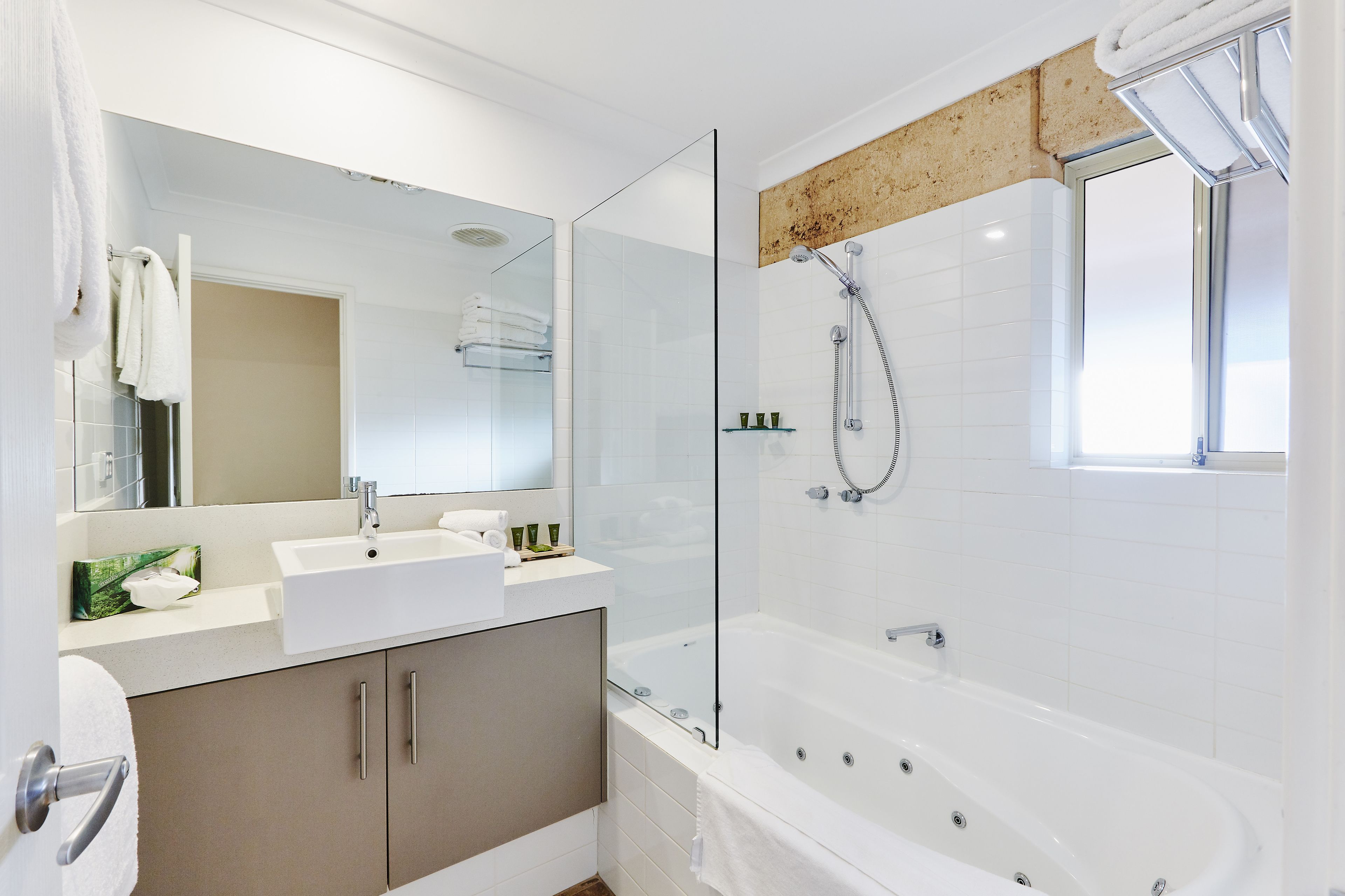 A modern bathroom with a glass-enclosed shower, a white sink, and a large bathtub.