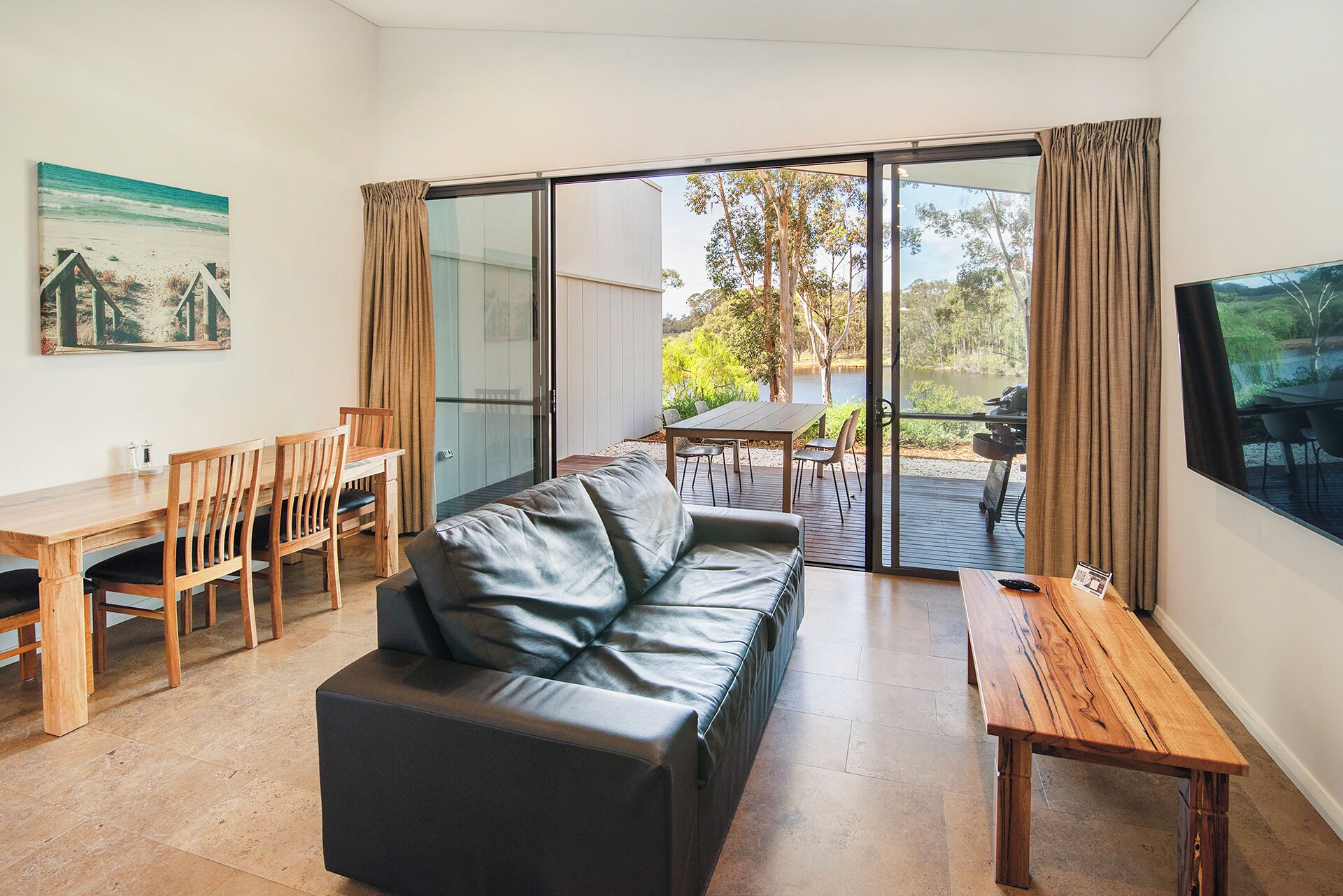 A modern living room with a sofa, dining table, chairs, and a TV.
