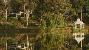 A modern house with a glass facade, surrounded by trees and a pond. - Eight Willows Retreat (Metricup)