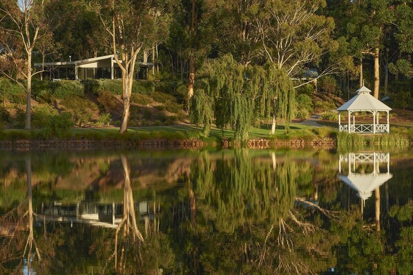 A modern house with a glass facade, surrounded by trees and a pond. - Eight Willows Retreat (Metricup)