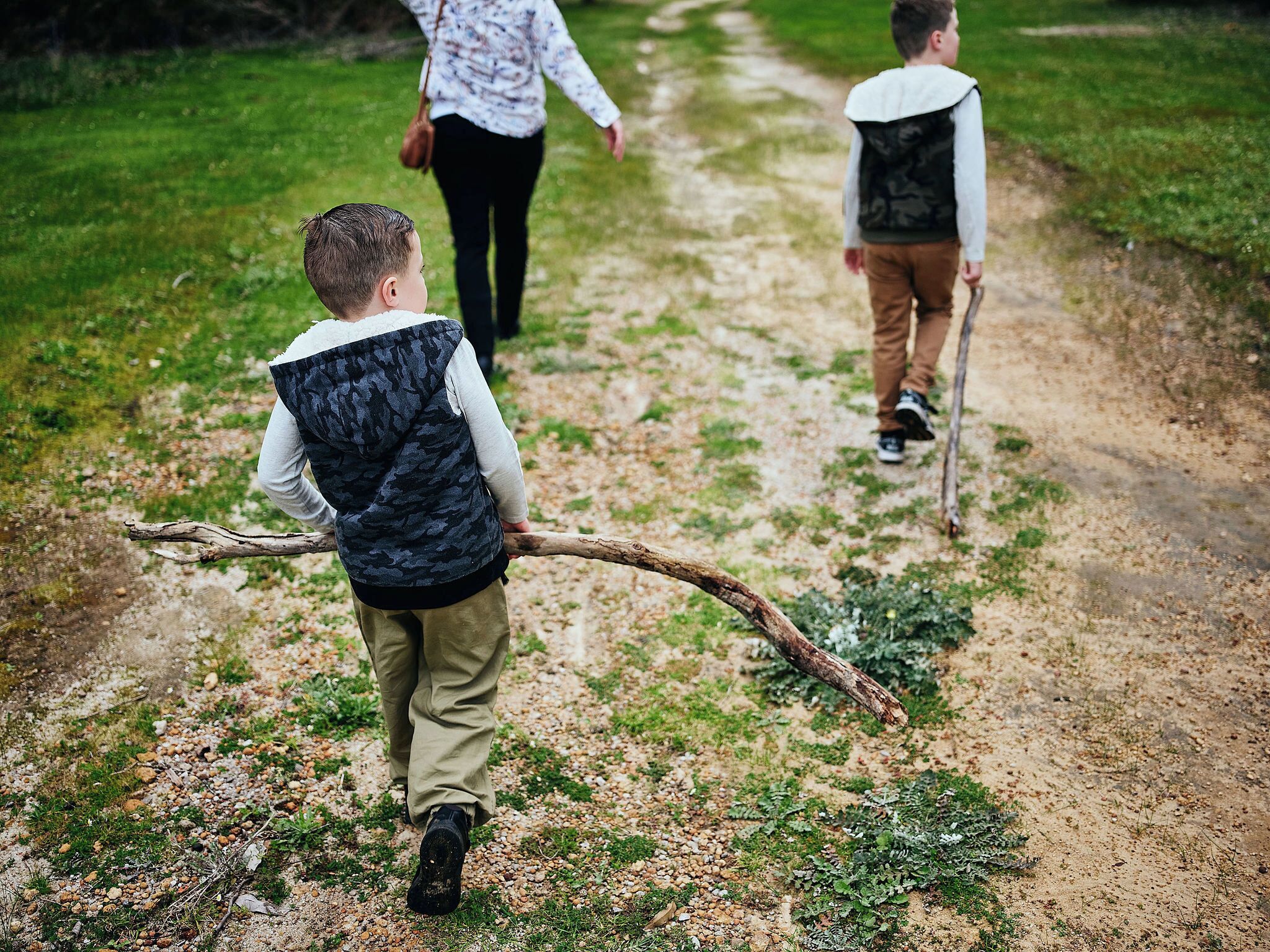 A dirt path with people walking, including a child with a walking stick.