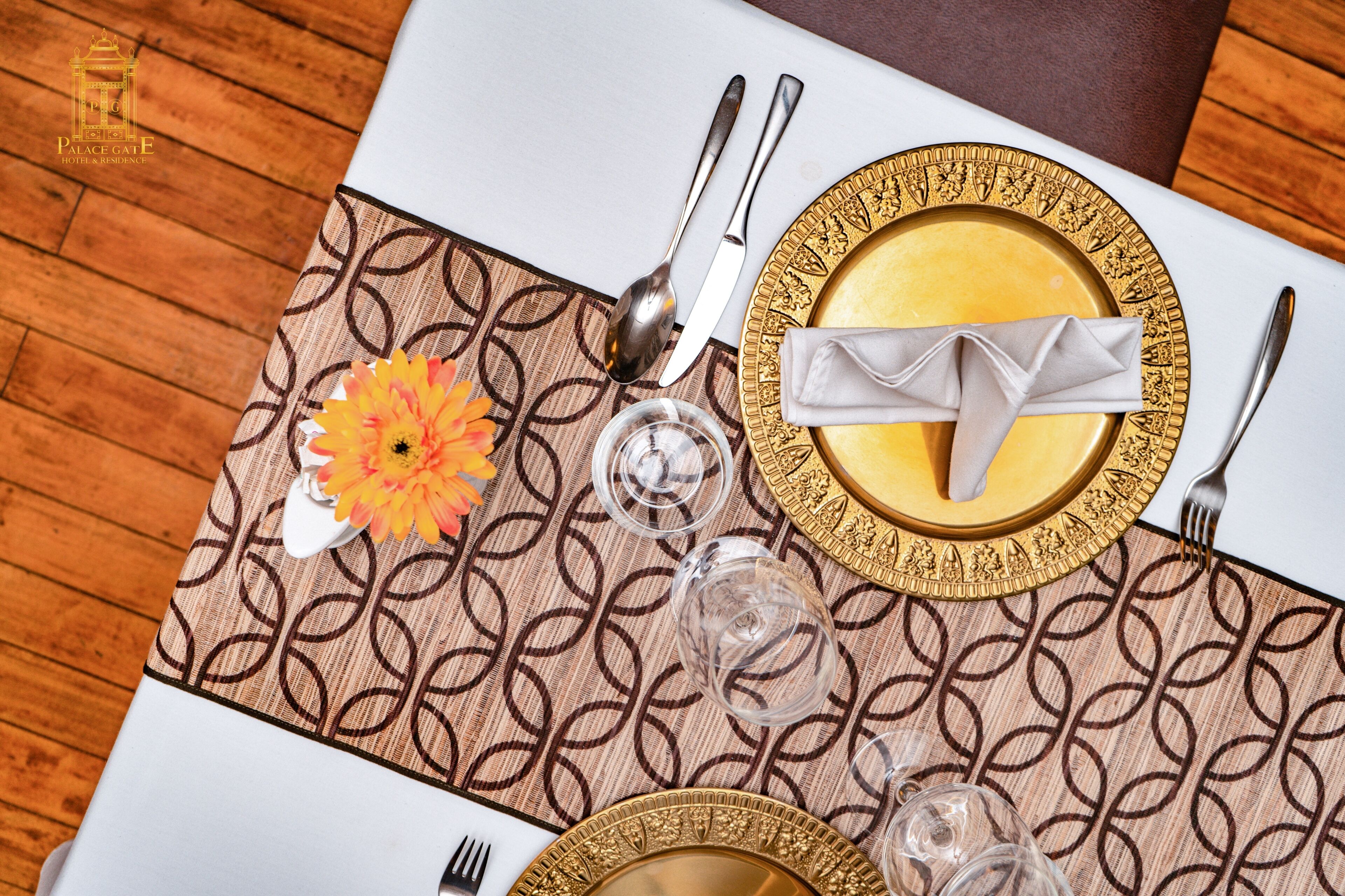 A table set with gold-rimmed plates, silverware, and a folded napkin.