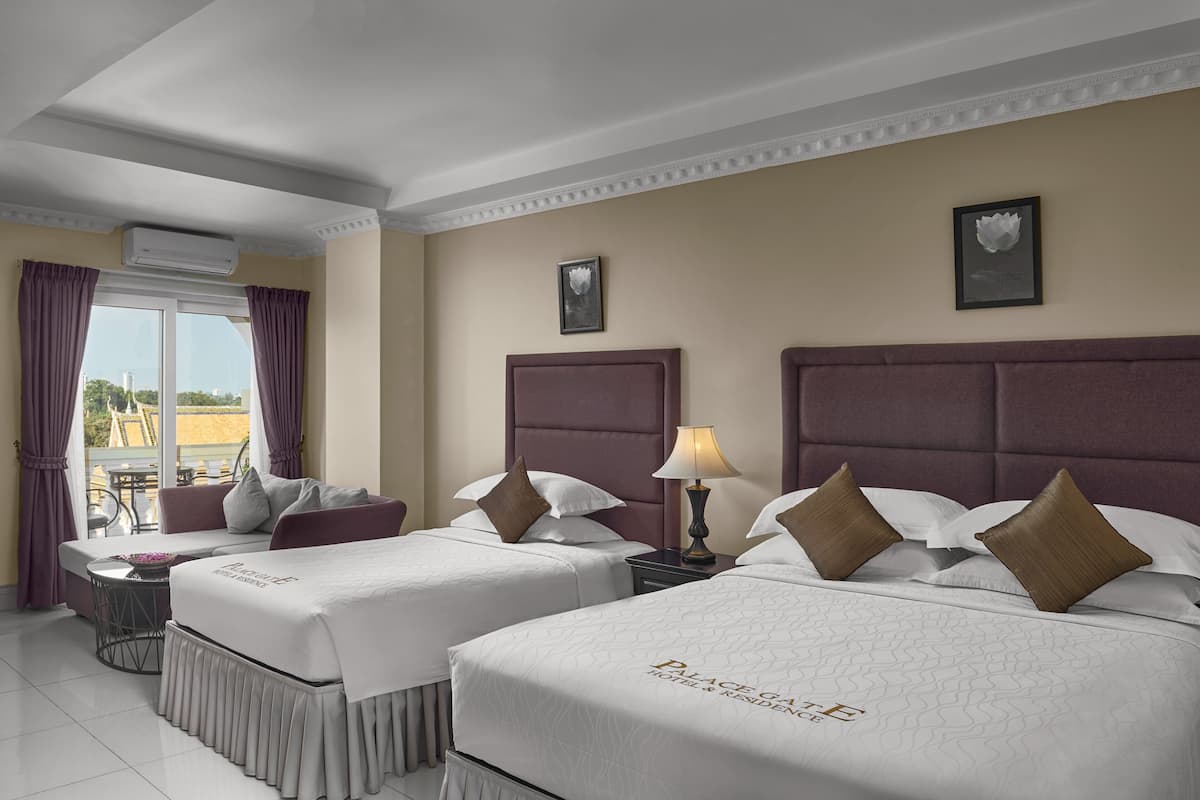 A hotel room with two beds, a sofa, a small table, and a balcony.