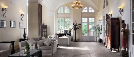A spacious living room with high ceilings, a chandelier, and large windows.