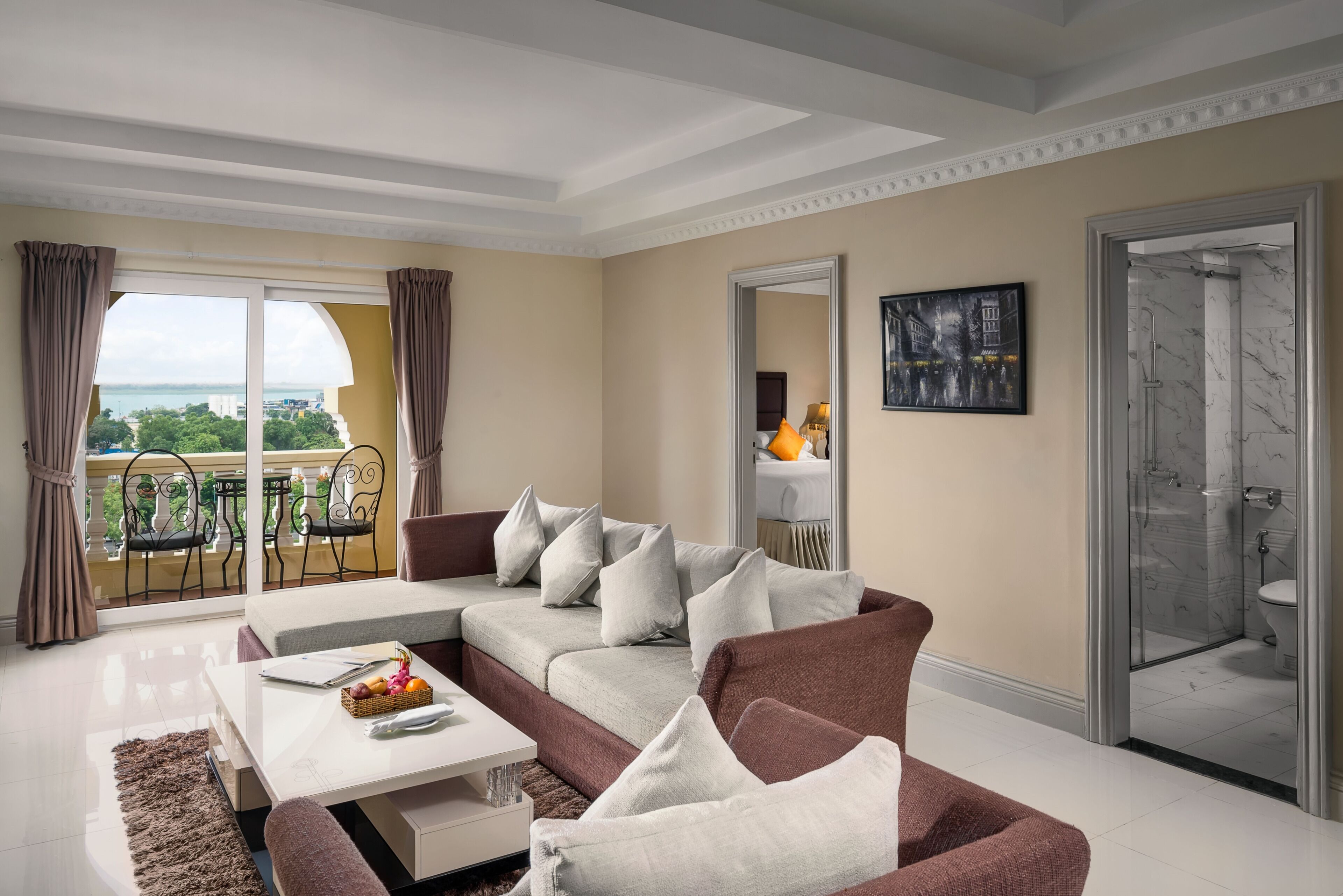A modern living room with a sofa, a coffee table, and a view of the outdoors through large windows.