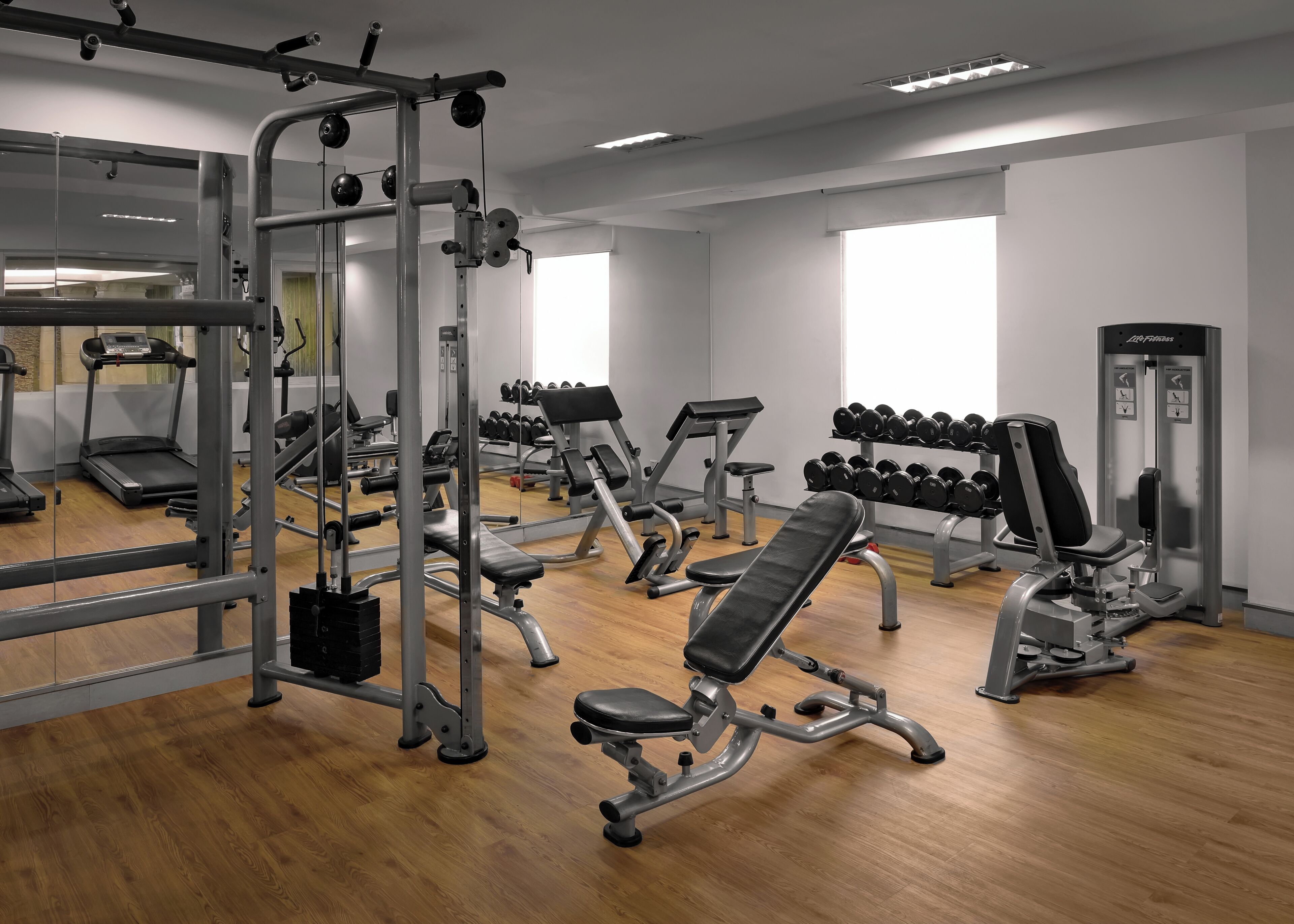 A gym with various exercise equipment, including treadmills, dumbbells, and weight machines.