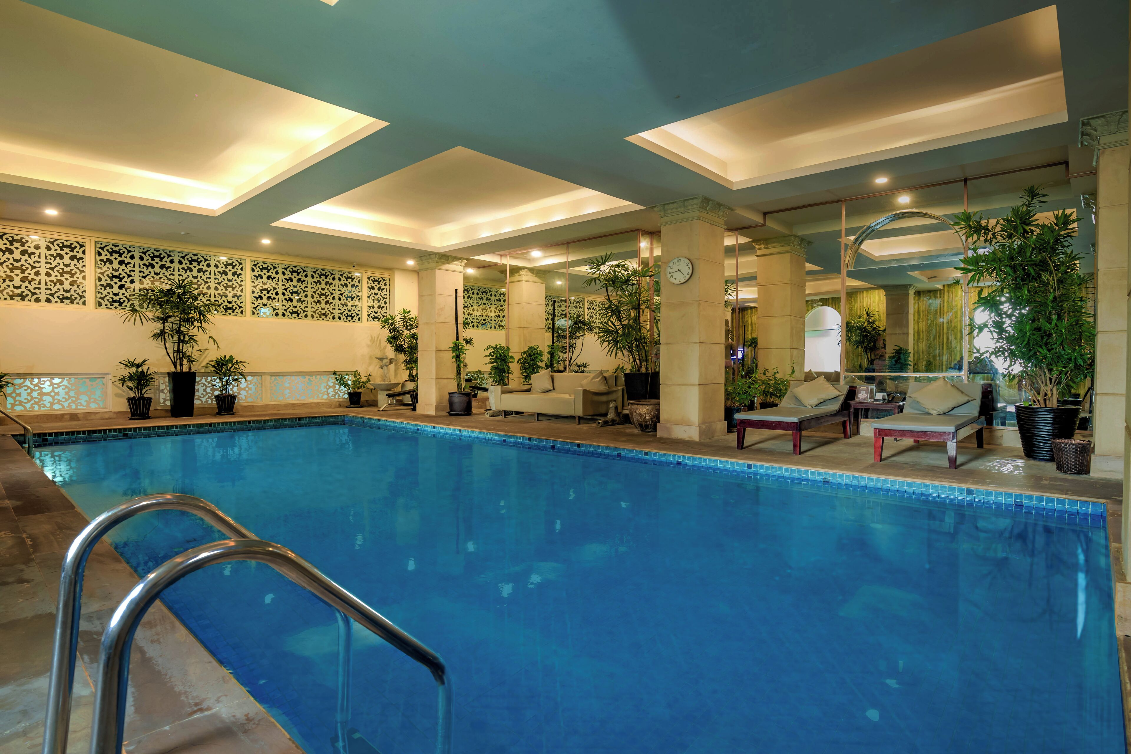 An indoor swimming pool with lounge chairs and potted plants.