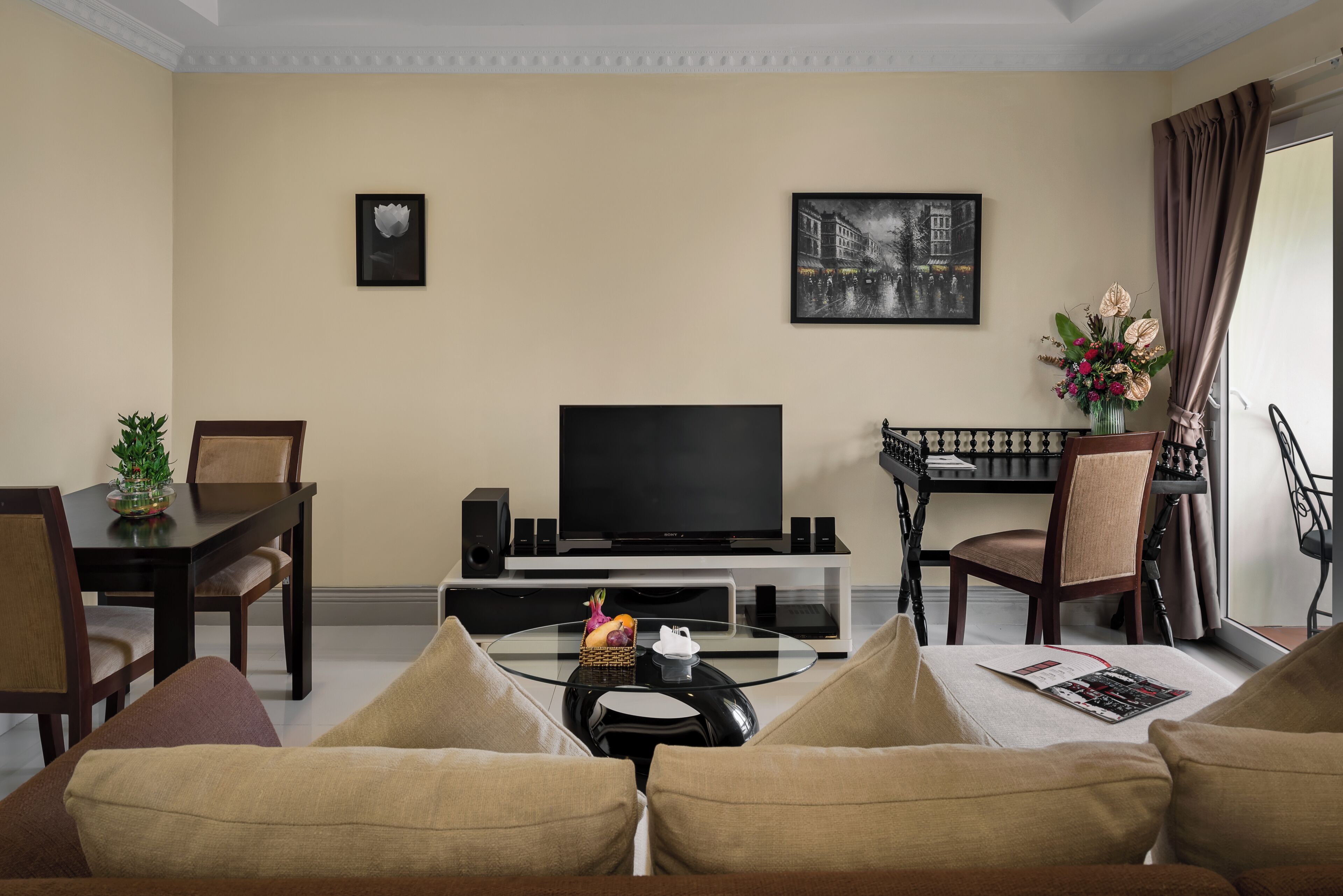 Una sala de estar con una televisión de pantalla plana, una mesa de comedor con sillas, un sofá y una mesa de centro con una revista.