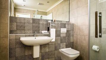 Un baño moderno con lavamanos, inodoro y zona de ducha.