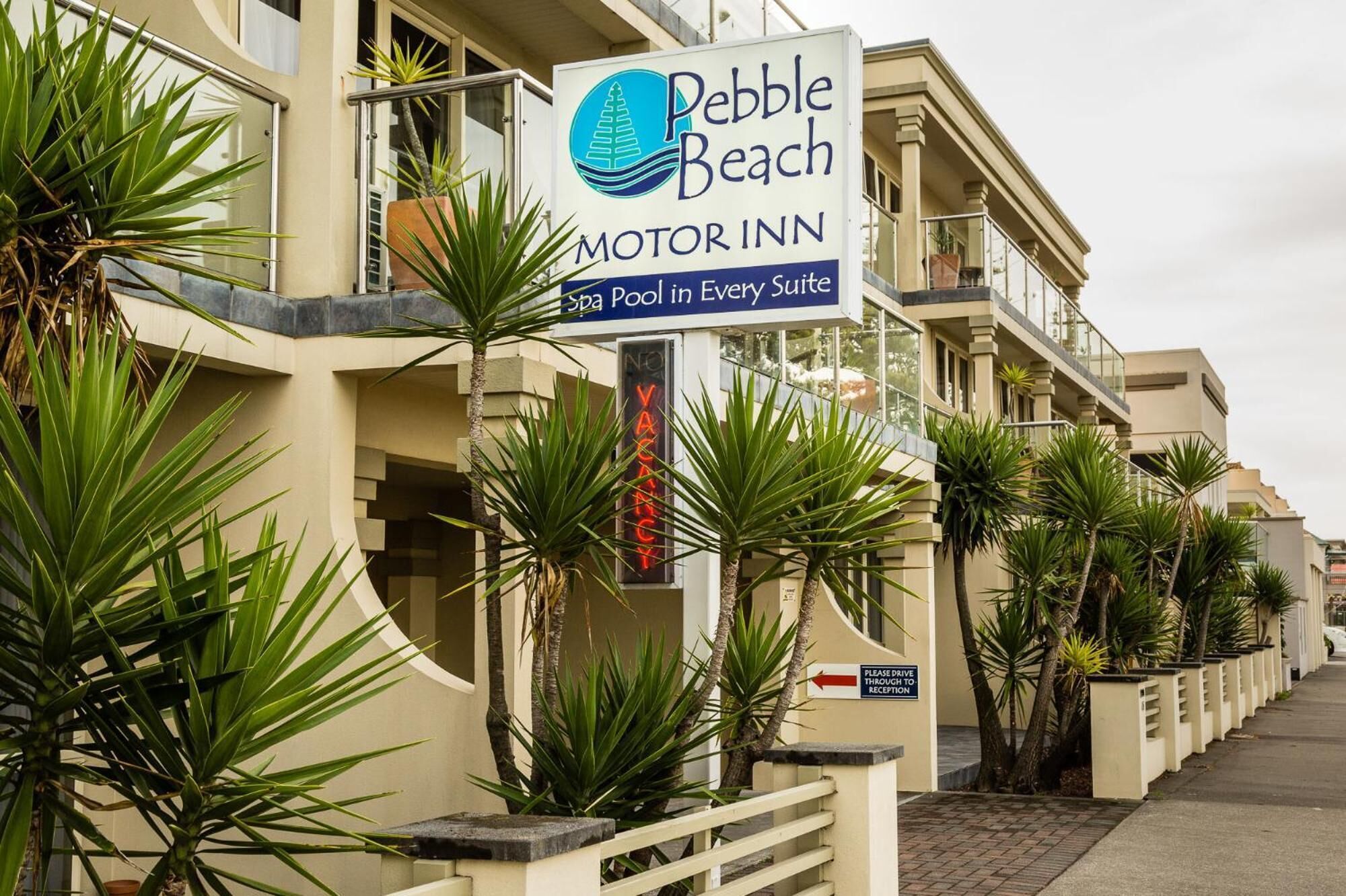 A hotel sign for Pebble Beach Motor Inn with a pool in every suite.