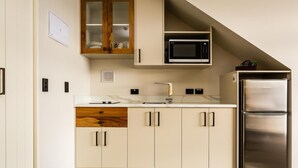 A modern kitchen with a built-in microwave, stainless steel refrigerator, and a wooden cabinet with glass doors.