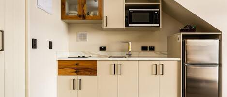 A modern kitchen with a built-in microwave, stainless steel refrigerator, and a wooden cabinet with glass doors.