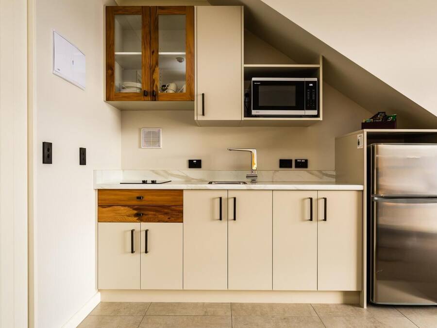A modern kitchen with a built-in microwave, stainless steel refrigerator, and a wooden cabinet with glass doors.