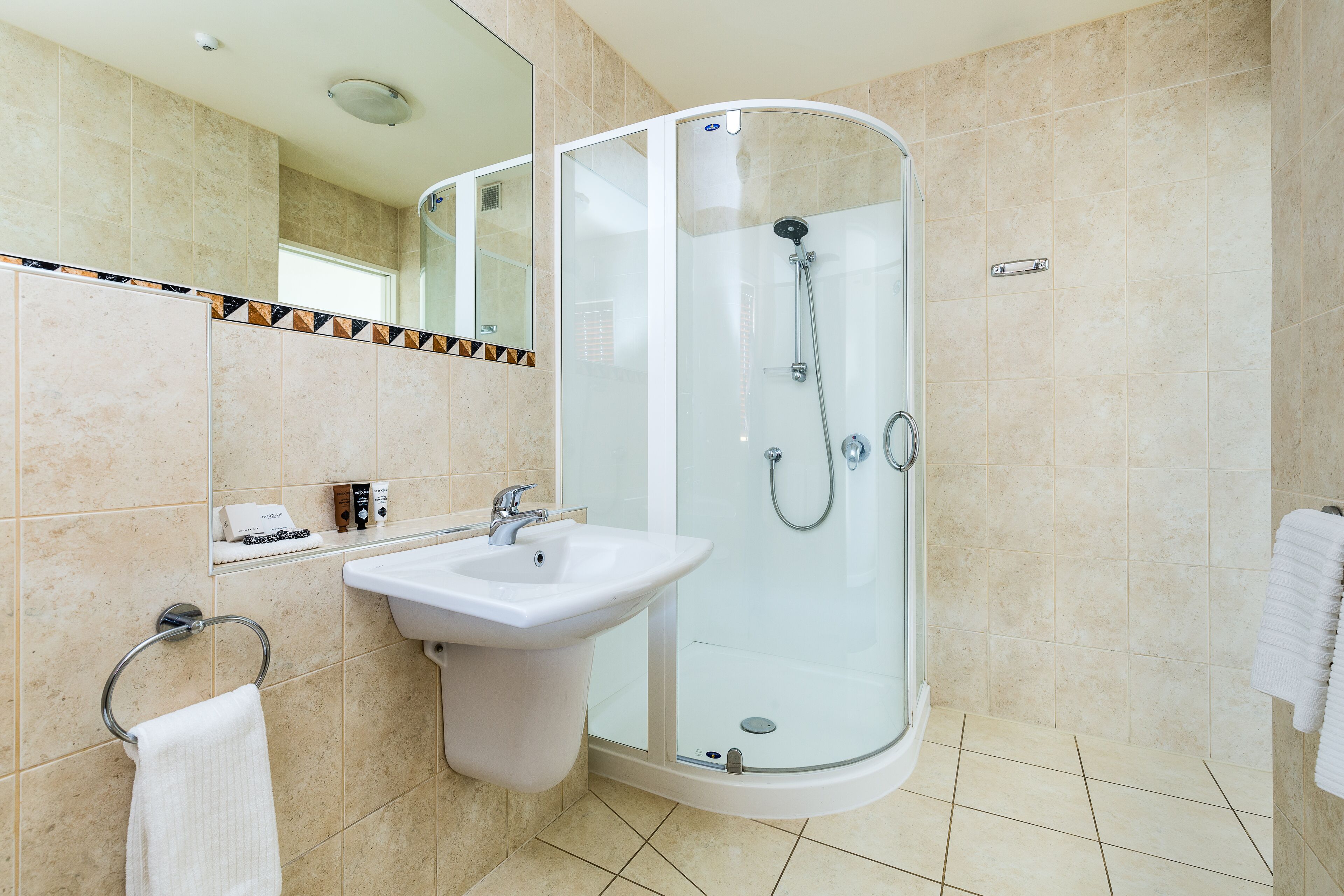 A modern bathroom with a glass-enclosed shower, a sink, and a mirror.