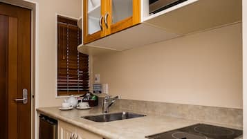 Una cocina con armarios blancos, una encimera de madera, un fregadero de acero inoxidable y un microondas integrado.