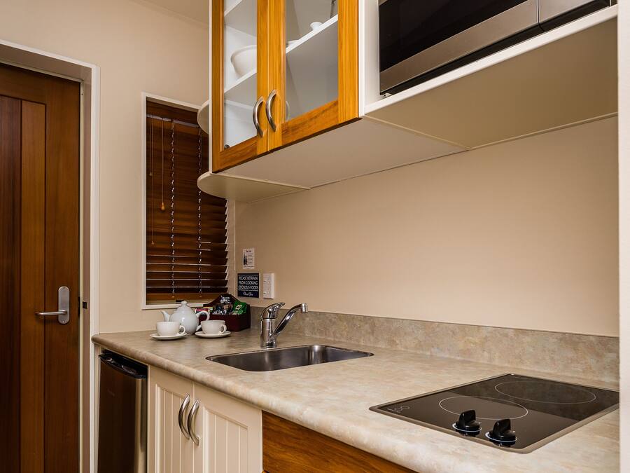 Una cocina con armarios blancos, una encimera de madera, un fregadero de acero inoxidable y un microondas integrado.