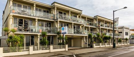 A multi-story hotel with balconies, potted plants, and a sign indicating a motor inn.