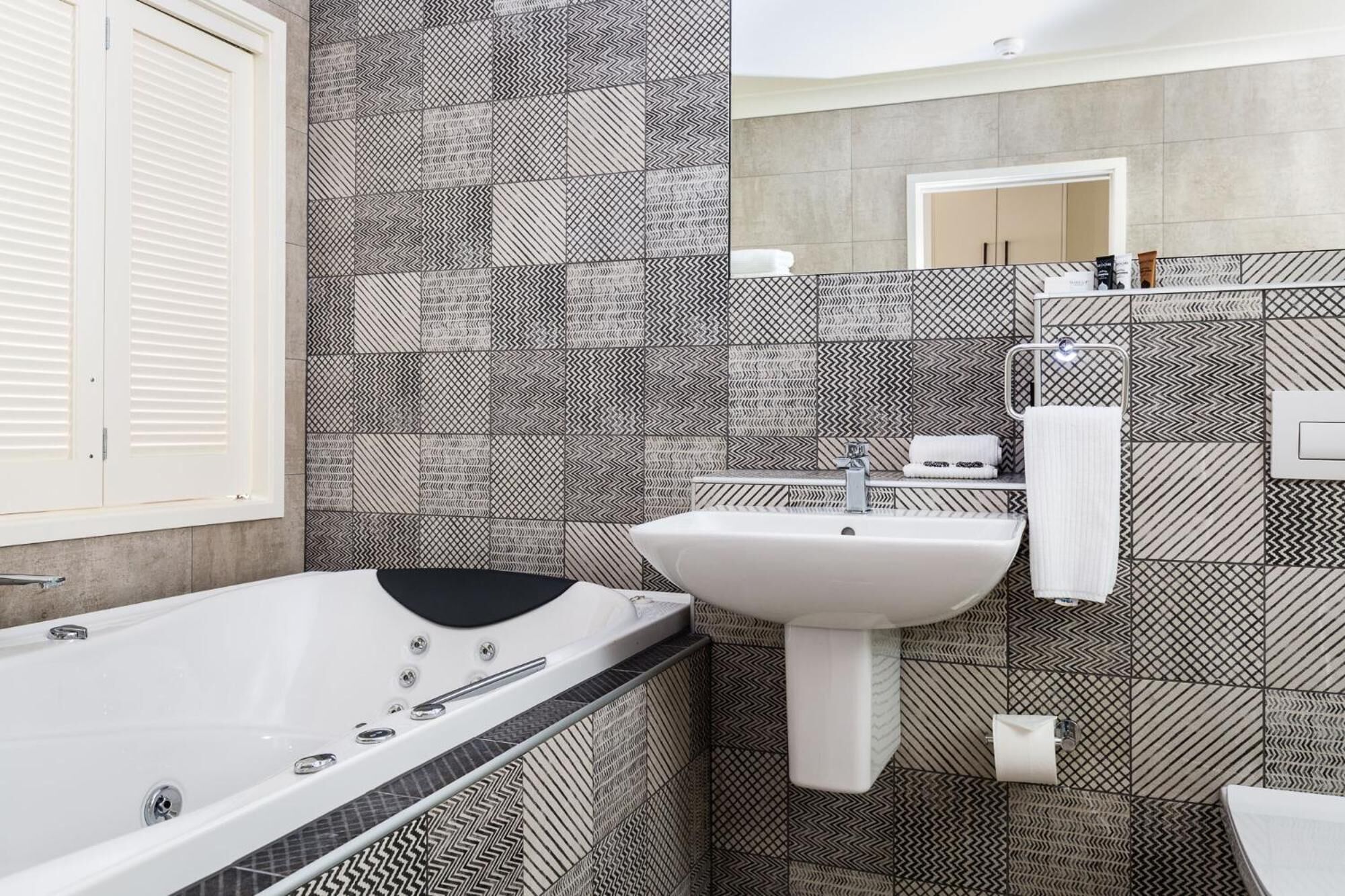 A modern bathroom with a freestanding bathtub, a sink, and a mirror.