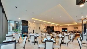 A spacious restaurant with modern decor, multiple dining tables, and chairs arranged in a clean, organized layout.