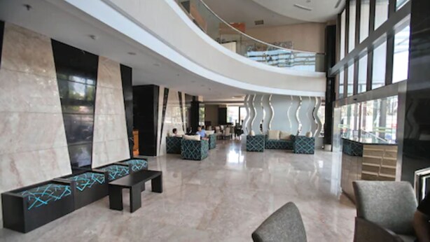 A spacious lobby with a curved ceiling, seating areas, and a view of the outside through large windows.