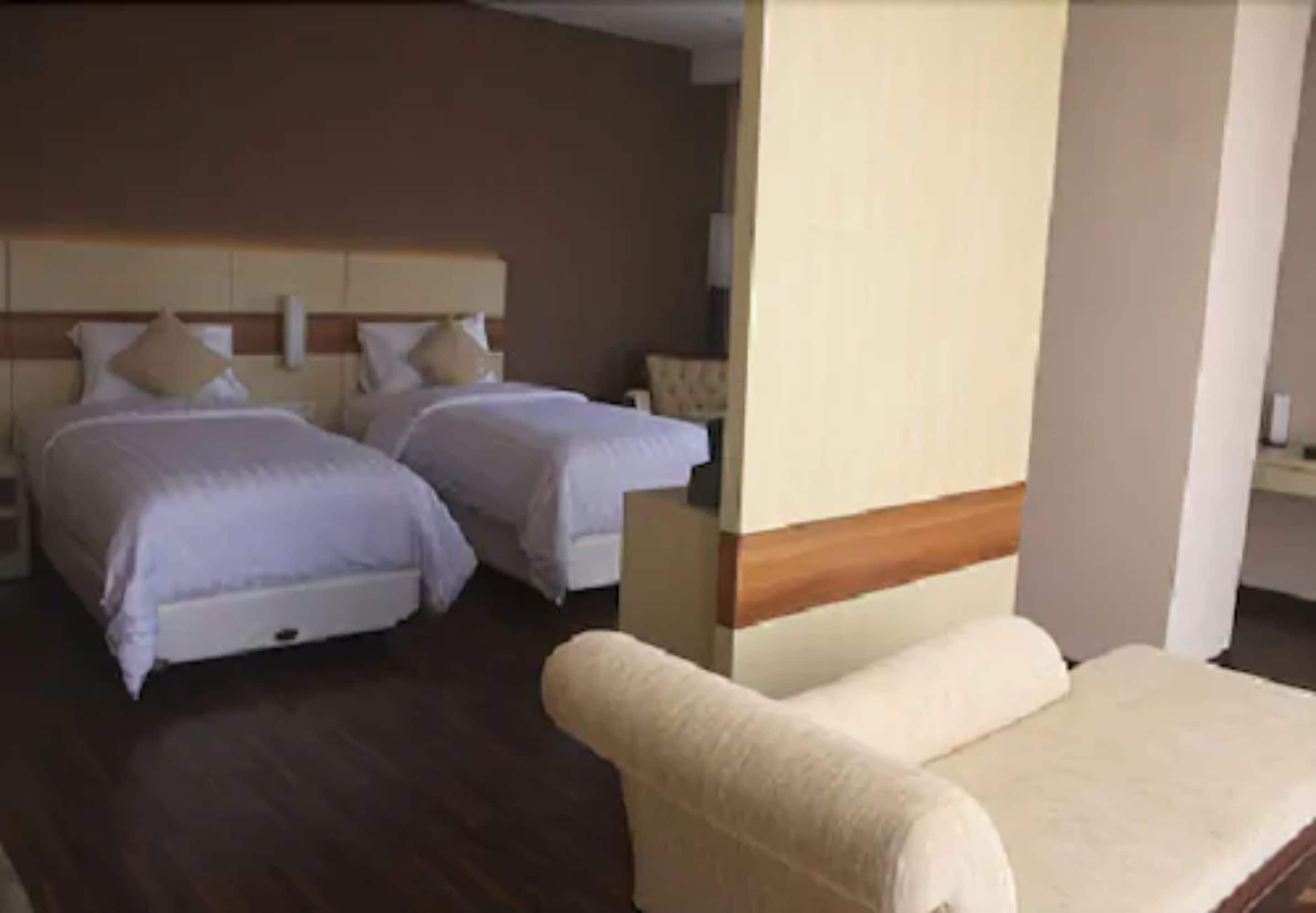 Ein Hotelzimmer mit zwei Betten, einem Sofa und einem hölzernen Kopfteil.