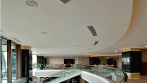 A modern interior with a curved glass railing, a central staircase, and a spacious area with seating and a fireplace.